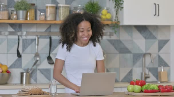 Mujer joven africana haciendo videollamada en el ordenador portátil en la cocina — Vídeo de stock