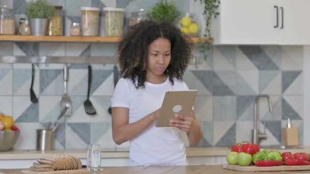 Joven mujer africana usando tableta en la cocina — Vídeo de stock