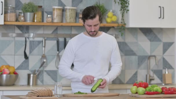 キッチンで魅力的な若い男の皮キュウリ — ストック動画