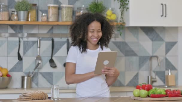 若いアフリカの女性がキッチンでタブレットでビデオ通話を行う — ストック動画