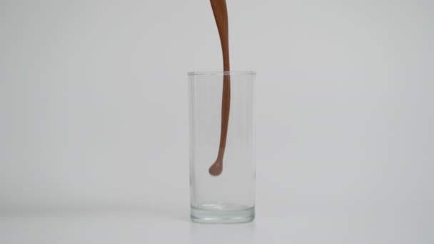 在玻璃杯中倒入巧克力牛奶的超级慢动作，蓝色背景 — 图库视频影像
