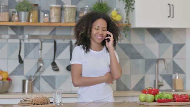 African Woman Talking on Smartphone while Standing in Kitchen — Stock Video