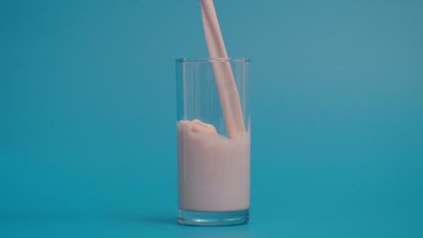 Mouvement super lent de verser le lait dans le verre, fond bleu — Video