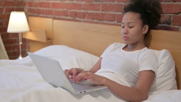 Mujer africana teniendo dolor de muñeca, trabajando en el ordenador portátil en la cama — Vídeos de Stock