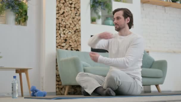 Jeune homme faisant des étirements sur tapis de yoga à la maison — Video