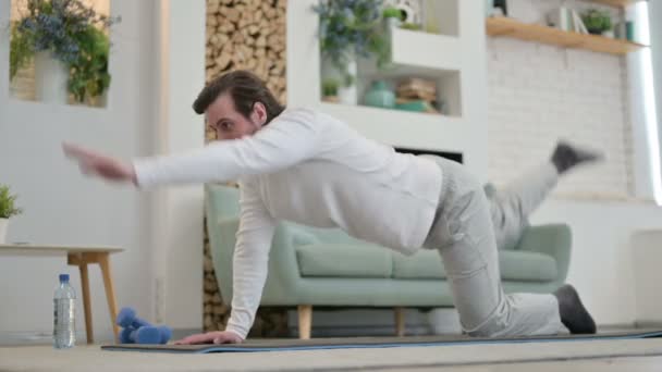 Jovem fazendo alongamentos no tapete de ioga em casa — Vídeo de Stock