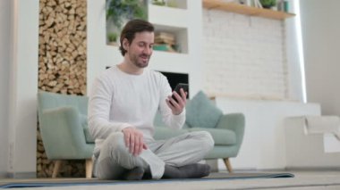 Video 'da konuşan genç adam Yoga Mat' te otururken akıllı telefondan arıyor. 