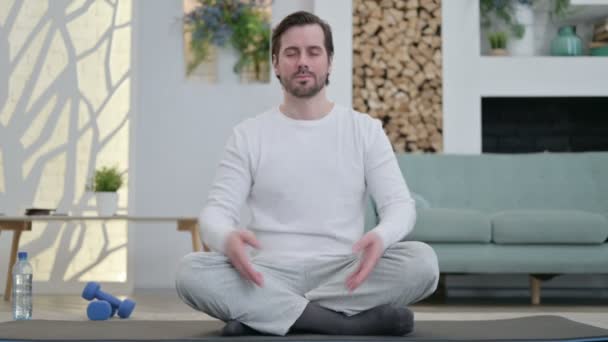 Porträtt av Unge man meditera på Yogamattan hemma — Stockvideo