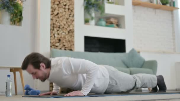 Zmęczony młody człowiek robi pompki na macie jogi w domu — Wideo stockowe