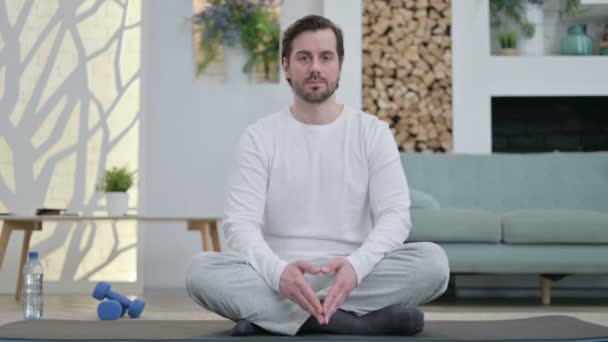 Retrato do jovem homem meditando no tapete de ioga em casa — Vídeo de Stock