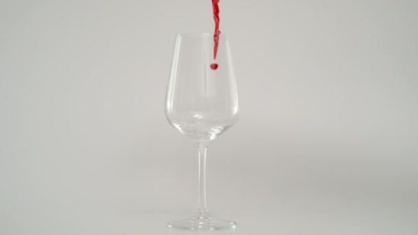 以1000 fps的速度在玻璃杯中倒入红酒的慢动作，红底 — 图库视频影像