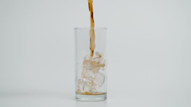 Langzame beweging van gietcola in glas met ijs, witte achtergrond — Stockvideo