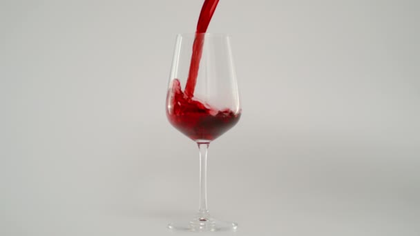 Наливаючи червоне вино в склянку зі швидкістю 1000 фунтів стерлінгів, супер повільний постріл, білий фон — стокове відео
