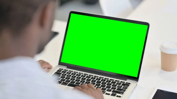 Hombre africano usando el ordenador portátil con la pantalla dominante verde del croma —  Fotos de Stock