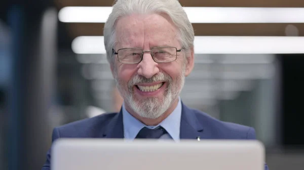 Close up de velho empresário com laptop sorrindo para a câmera — Fotografia de Stock