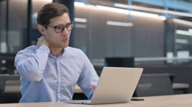 Dizüstü bilgisayarı olan genç adam boyun ağrısı çekiyor.