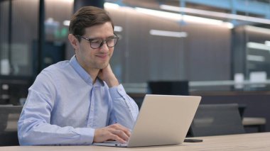 Dizüstü bilgisayarı olan genç adam boyun ağrısı çekiyor.