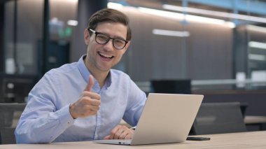 Dizüstü bilgisayarlı Genç Adam Başparmağını kaldırdı