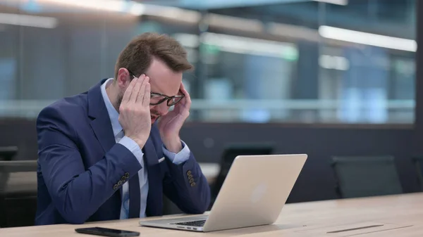 Empresário de meia-idade com laptop com dor de cabeça — Fotografia de Stock