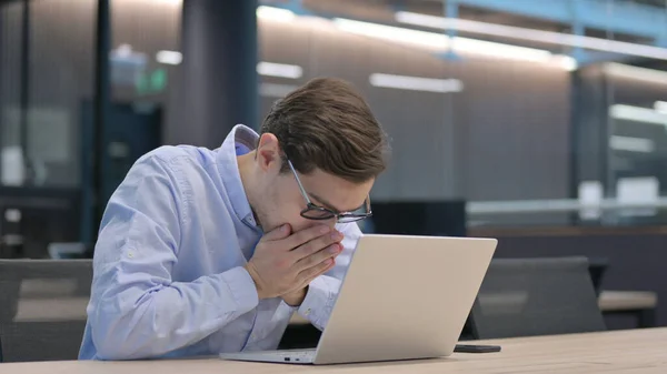 Jovem com espirros de laptop no escritório — Fotografia de Stock