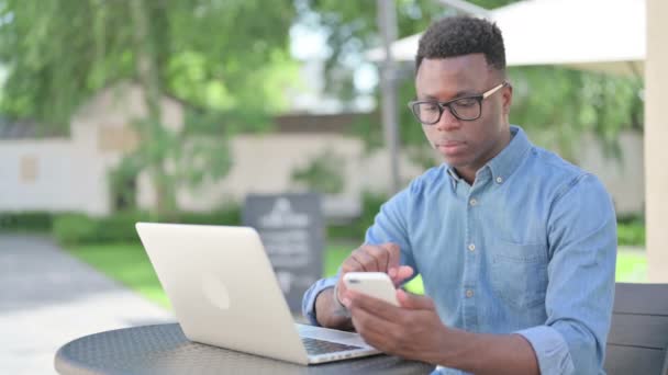 Attraktiv afrikansk man använder smartphone i Outdoor Cafe — Stockvideo
