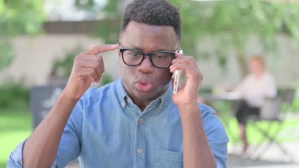 Dühös afrikai férfi portréja Okostelefonon beszél — Stock videók