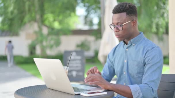 Hombre africano con café trabajando en el ordenador portátil en el café al aire libre — Vídeos de Stock