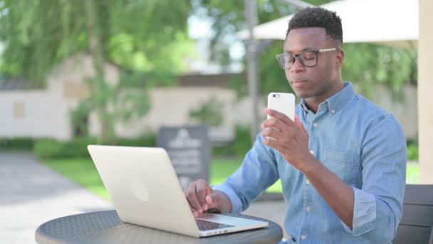 Homem africano falando no smartphone no café ao ar livre — Vídeo de Stock