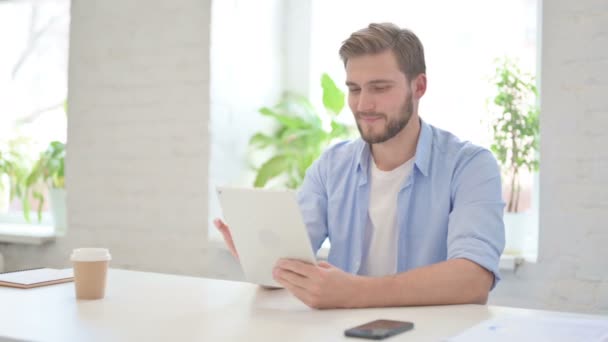 Ελκυστικός νεαρός δημιουργός χρησιμοποιώντας Tablet στο σύγχρονο γραφείο — Αρχείο Βίντεο
