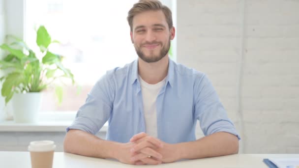 Молодий креативний чоловік посміхається на камеру в сучасному офісі — стокове відео
