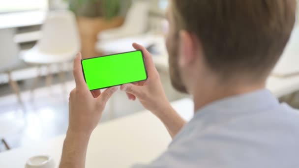Young Creative Man op zoek naar Smartphone met Chroma Screen — Stockvideo