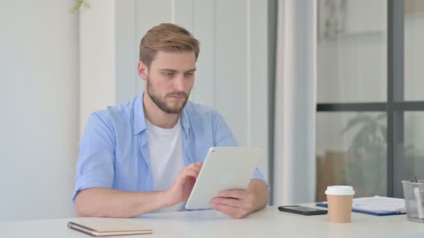 Aantrekkelijke jonge creatieve man met behulp van Tablet in Office — Stockvideo