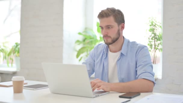Homem criativo olhando para a câmera ao usar o laptop no escritório moderno — Vídeo de Stock
