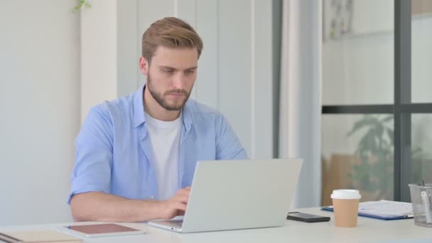 Jovem homem criativo trabalhando no laptop no escritório — Vídeo de Stock