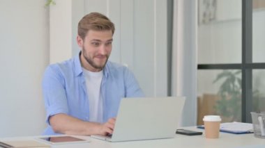 Dizüstü bilgisayarda kutlama yapan başarılı genç yaratıcı adam. 