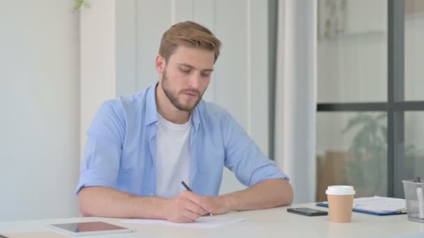 Offensiver junger Kreativer, der auf Papier schreibt und denkt — Stockvideo