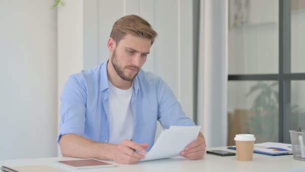 Joven hombre creativo leyendo documentos en la oficina — Vídeo de stock