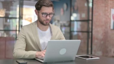 İş yerinde dizüstü bilgisayarda çalışan genç adam. 