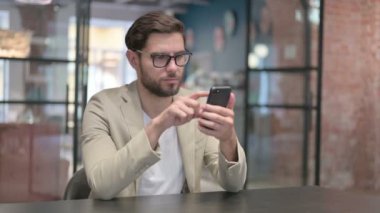 İş yerinde akıllı telefon kullanan çekici genç adam. 