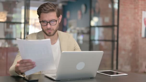 Hombre con Laptop lectura de documentos en el trabajo — Vídeo de stock