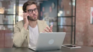 Dizüstü bilgisayarı olan agresif adam telefonda sinirleniyor. 