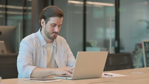 Hombre adulto maduro mirando la cámara mientras usa el ordenador portátil en la oficina — Vídeos de Stock