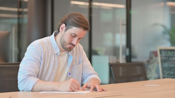 Hombre adulto maduro que enfrenta dificultades mientras escribe en papel — Vídeo de stock