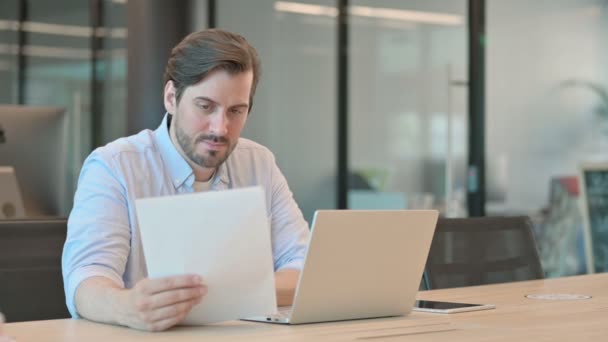 Reifer erwachsener Mann mit Laptop hat Erfolg beim Lesen von Dokumenten — Stockvideo