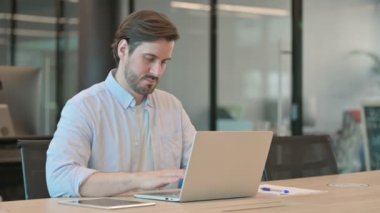 Dizüstü bilgisayarı olan yetişkin bir adamın baş ağrısı var. 