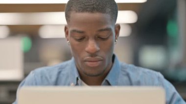Genç Afro-Amerikan adam dizüstü bilgisayarla çalışıyor.