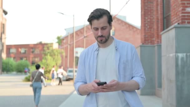 Mann benutzt Smartphone beim Gehen auf der Straße — Stockvideo
