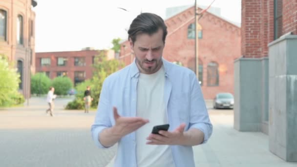 Hombre teniendo pérdida en el teléfono mientras camina en la calle — Vídeos de Stock