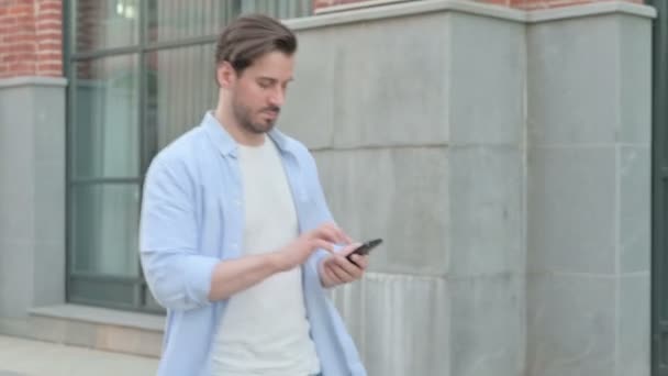 Hombre hablando por teléfono mientras camina en la calle — Vídeos de Stock