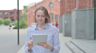 Sokakta yürürken Tablet üzerinde çalışan kadın